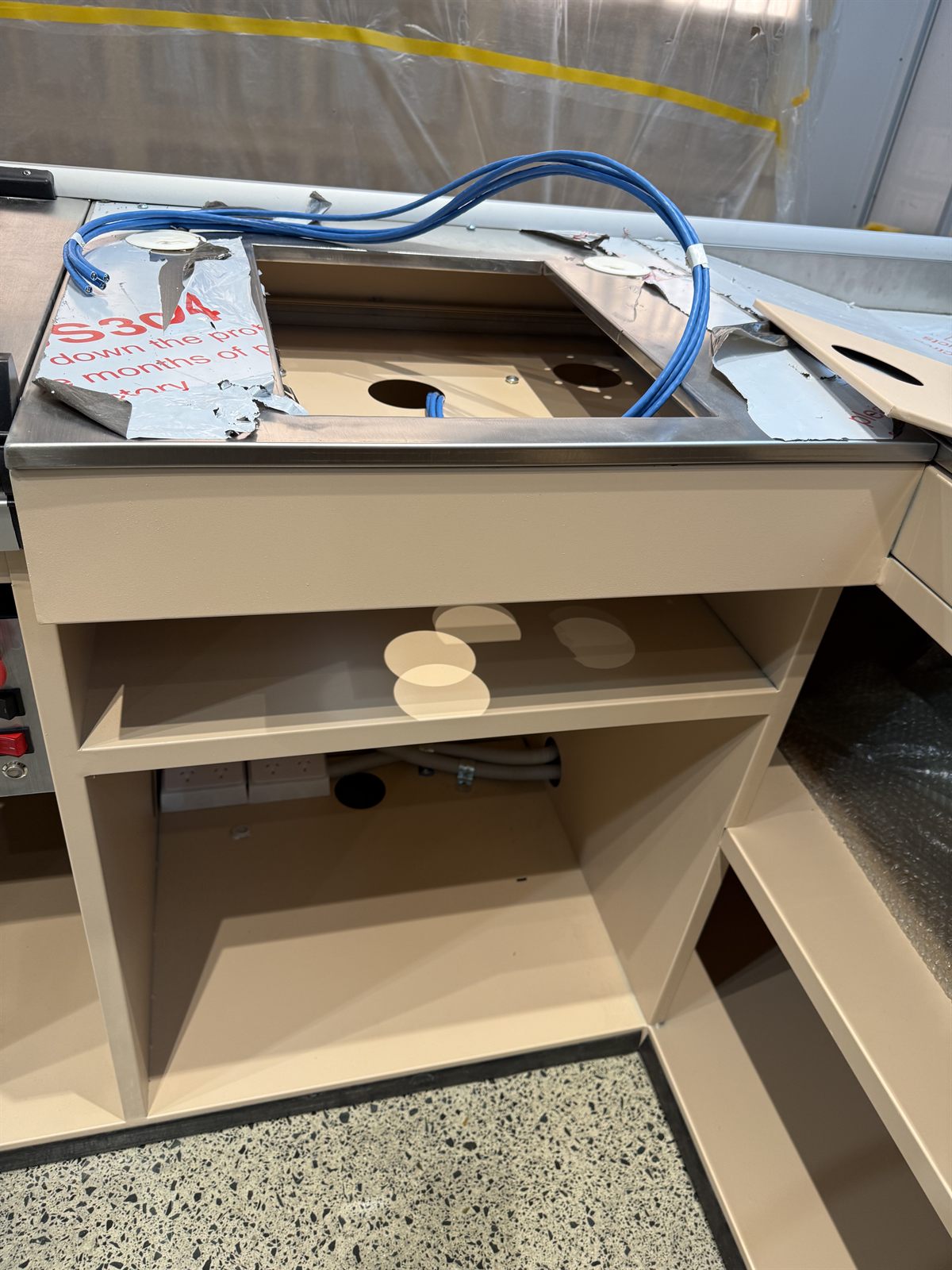 Checkout cabinet with blue cabling prepared for POS equipment