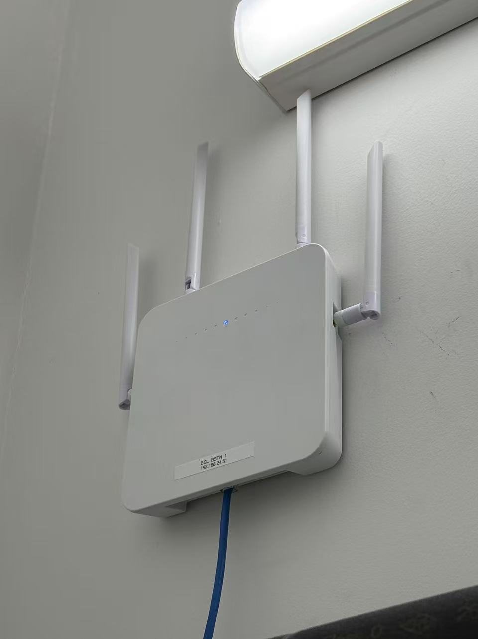 Wireless network device mounted on a wall with blue cabling