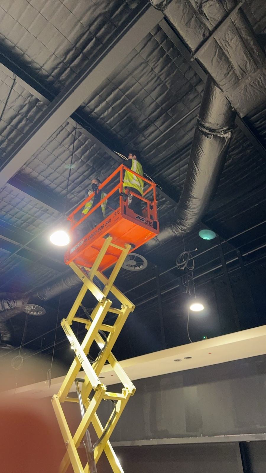 Technicians using lift access for ceiling installation work