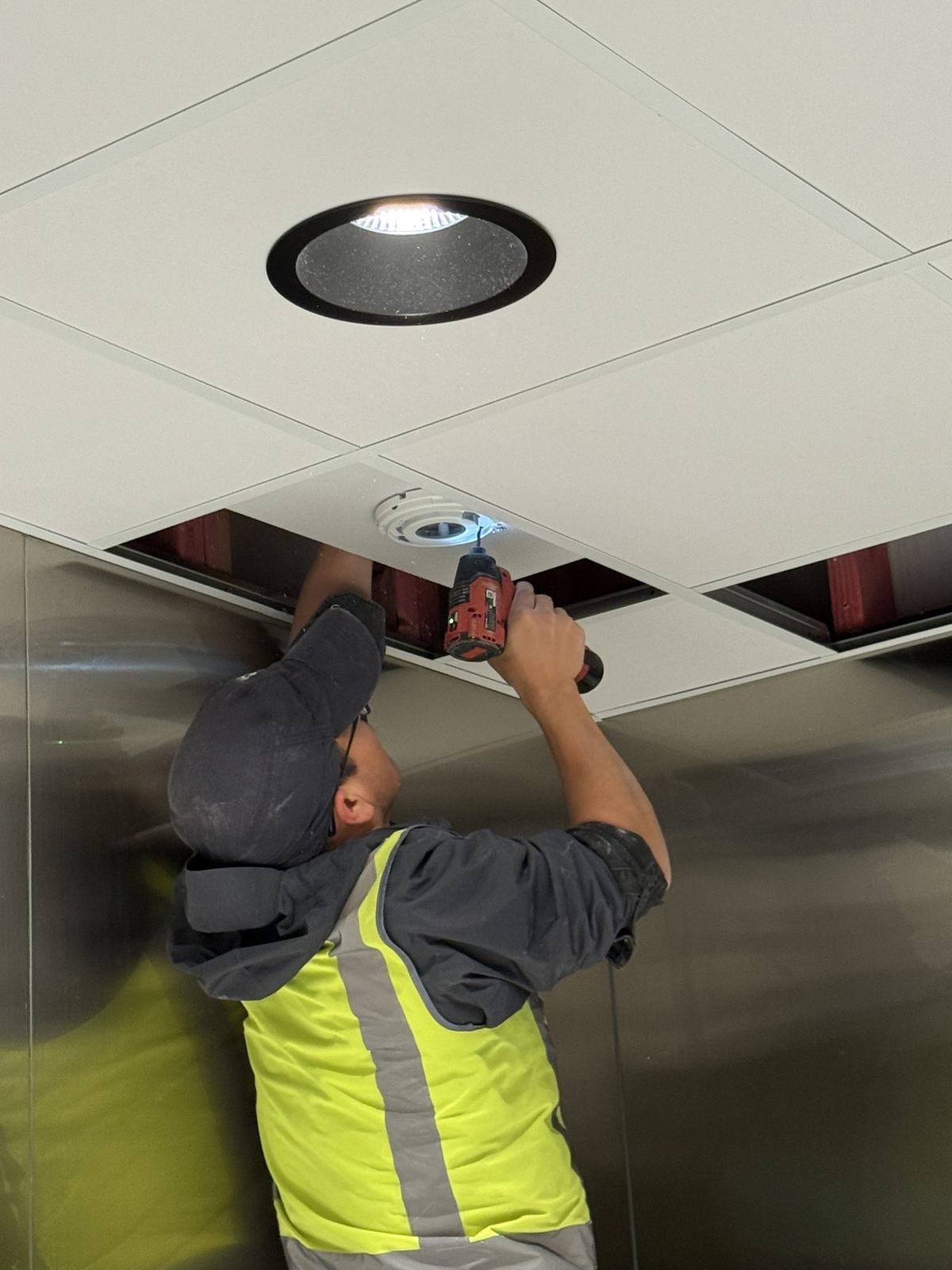Technician installing a CCTV camera into a ceiling panel
